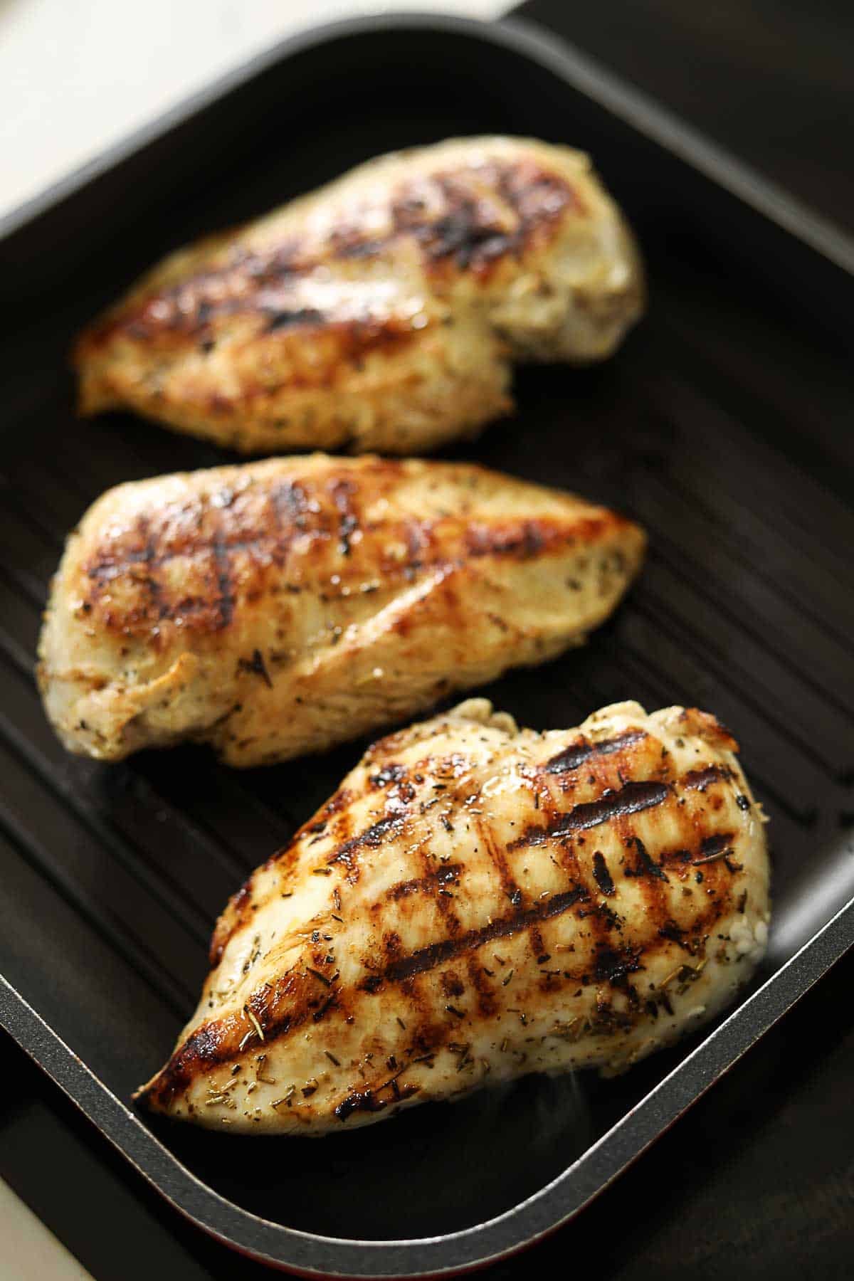 Chicken breasts in a grill pan, fully grilled with char marks.