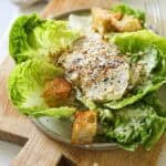 Grilled Chicken Caesar Salad on a plate with croutons and grated parmesan cheese.