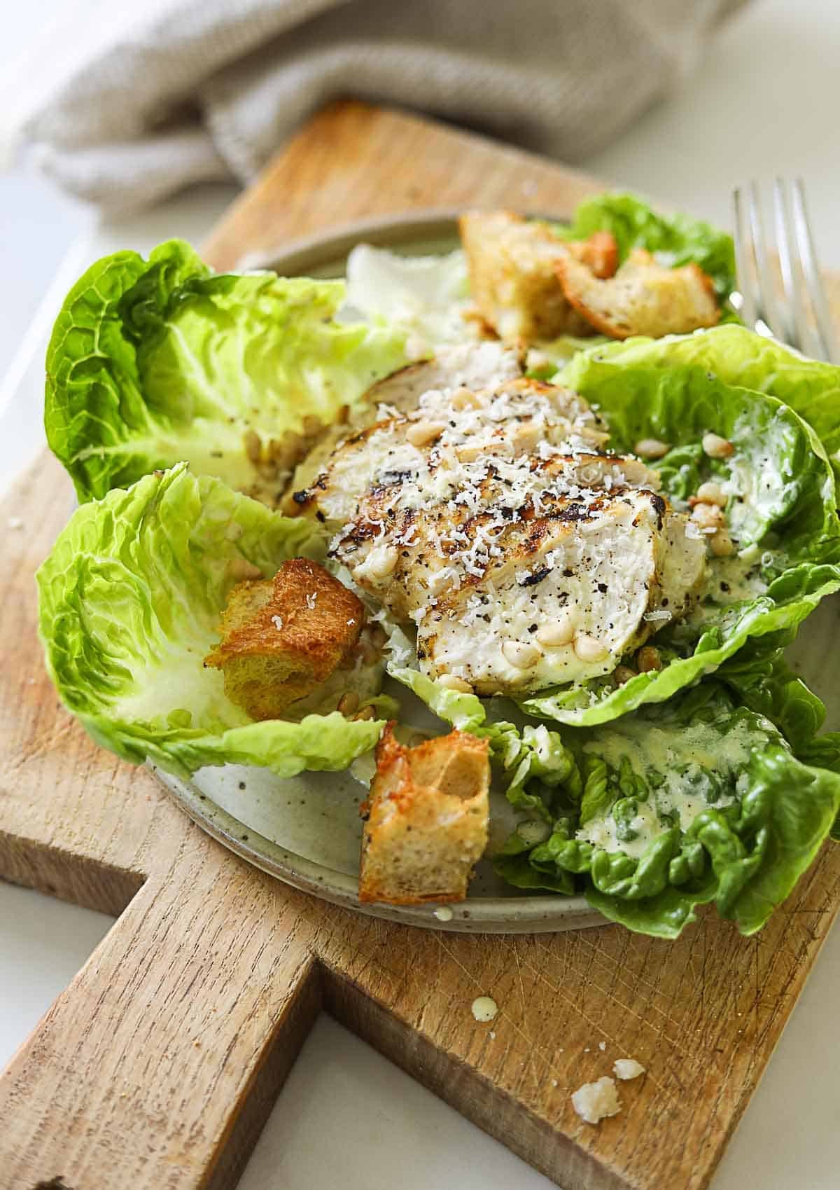 Grilled Chicken Caesar Salad on a plate with croutons and grated parmesan cheese.