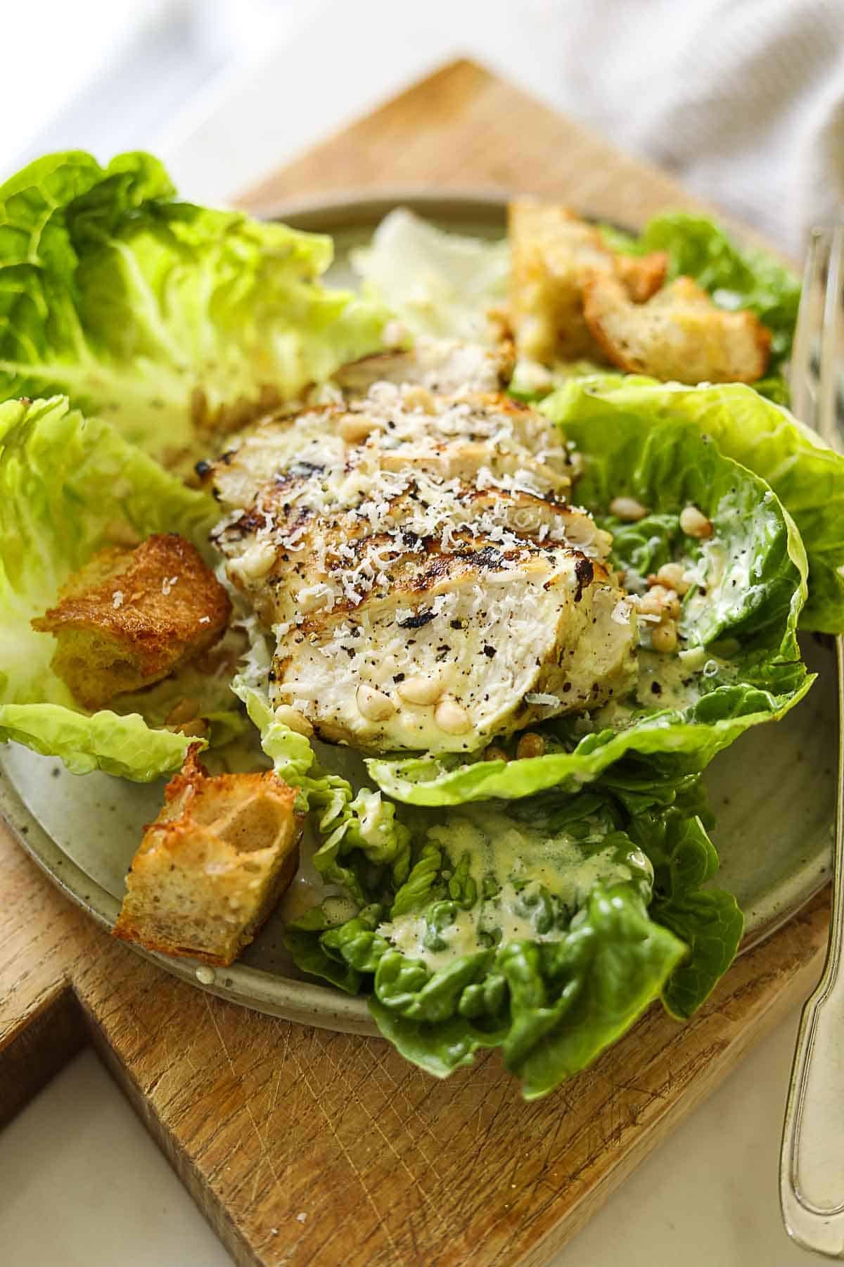 Close up ogf a caesar salad with grilled chicken on top.