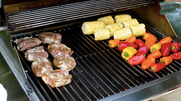 Chicken thighs and vegetables grilling on a BBQ