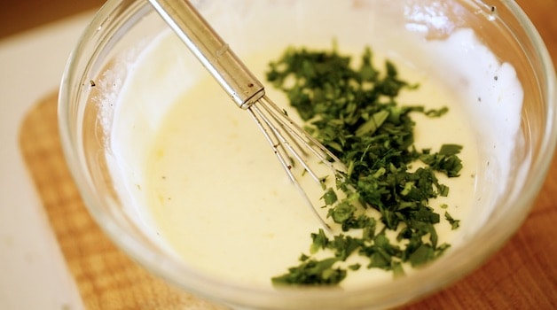 A bowl of yogurt sauce with fresh herbs