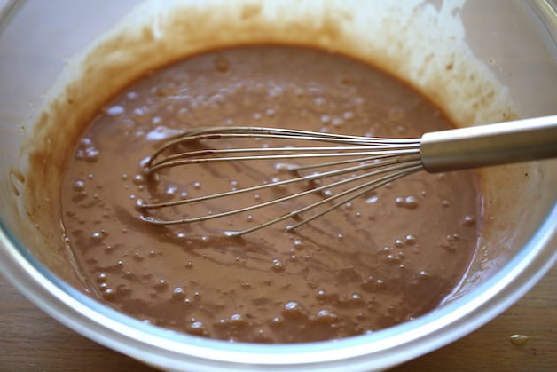 Mixing batter of Nutella, Sweetened Condensed Milk and Heavy Cream in a large clear bowl with whisk