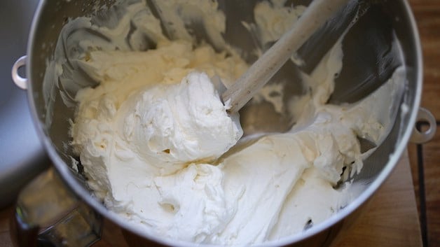 Spatula in a metal mixing bowl of whipped cream 