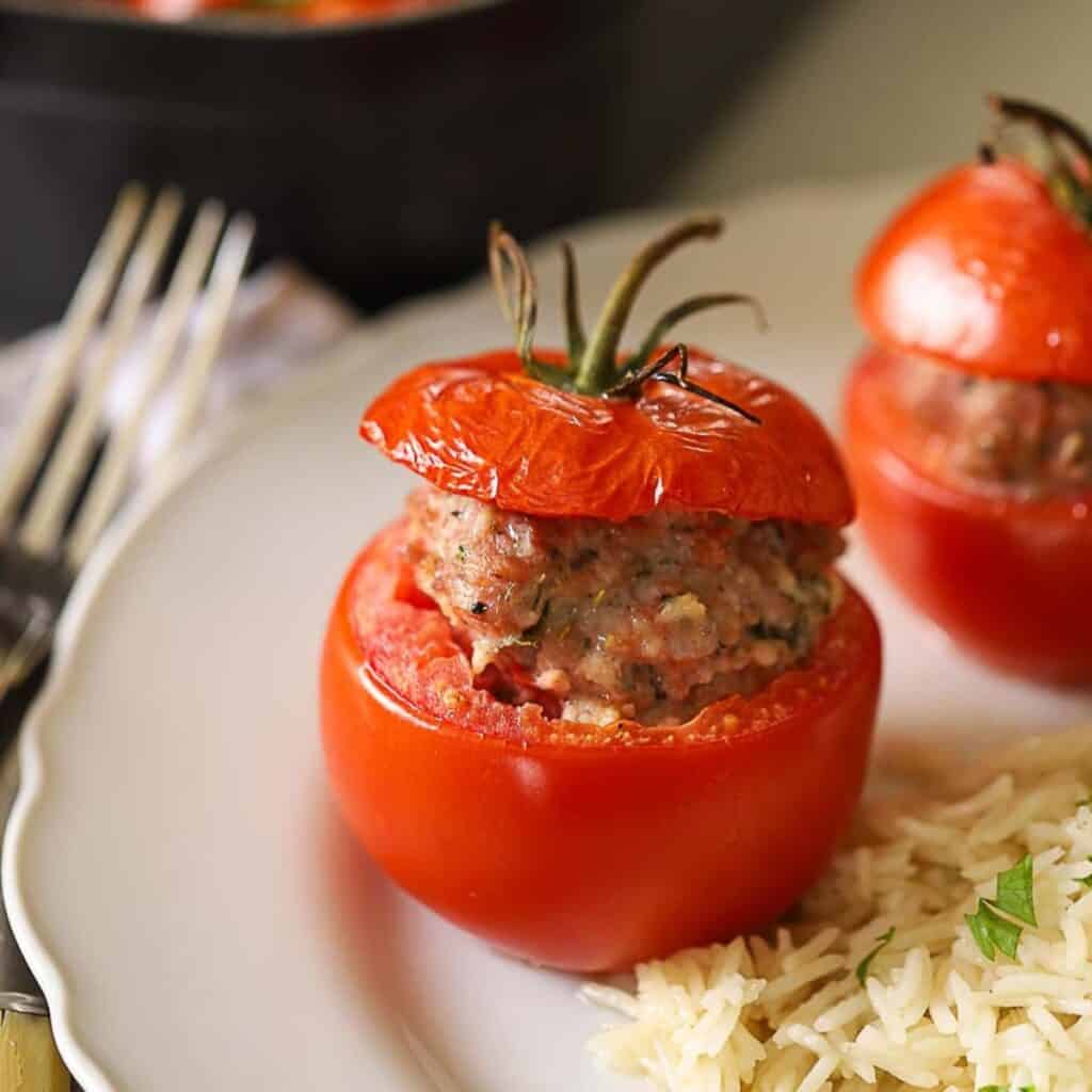 Stuffed tomatoes on a plate with rice.