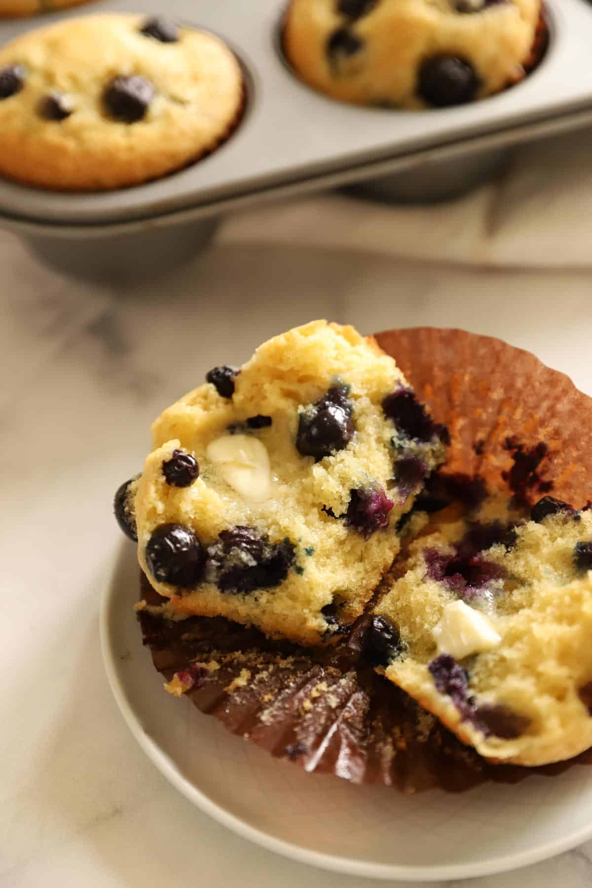 a freshly baked blueberry muffin, split open with melted butter