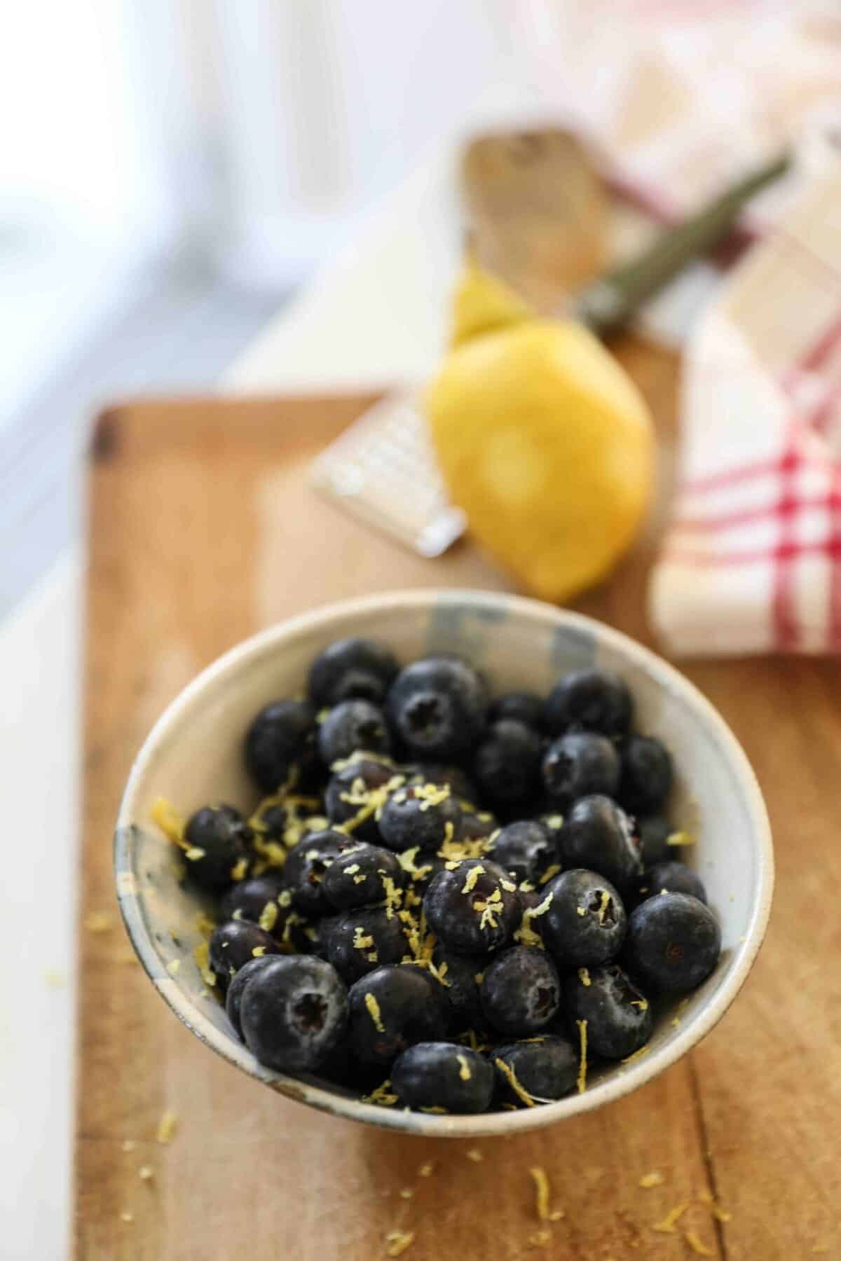 Blueberries in a bowl with lemon zest on top.