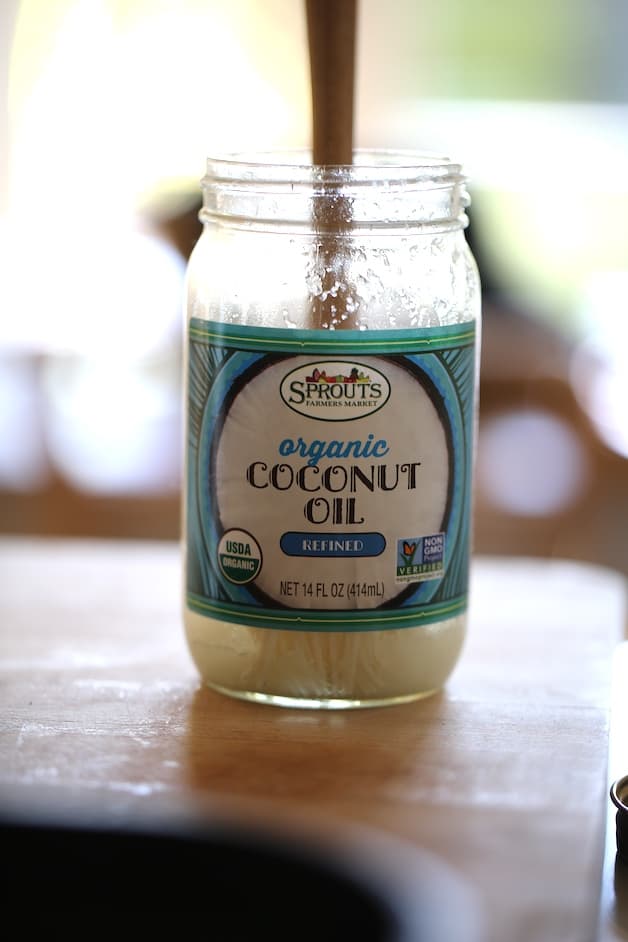 a jar of coconut oil on a cutting board