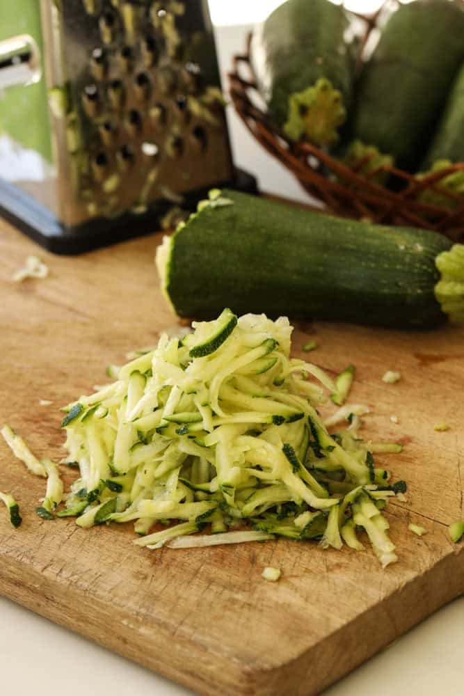 Grating zucchini with a box grater.