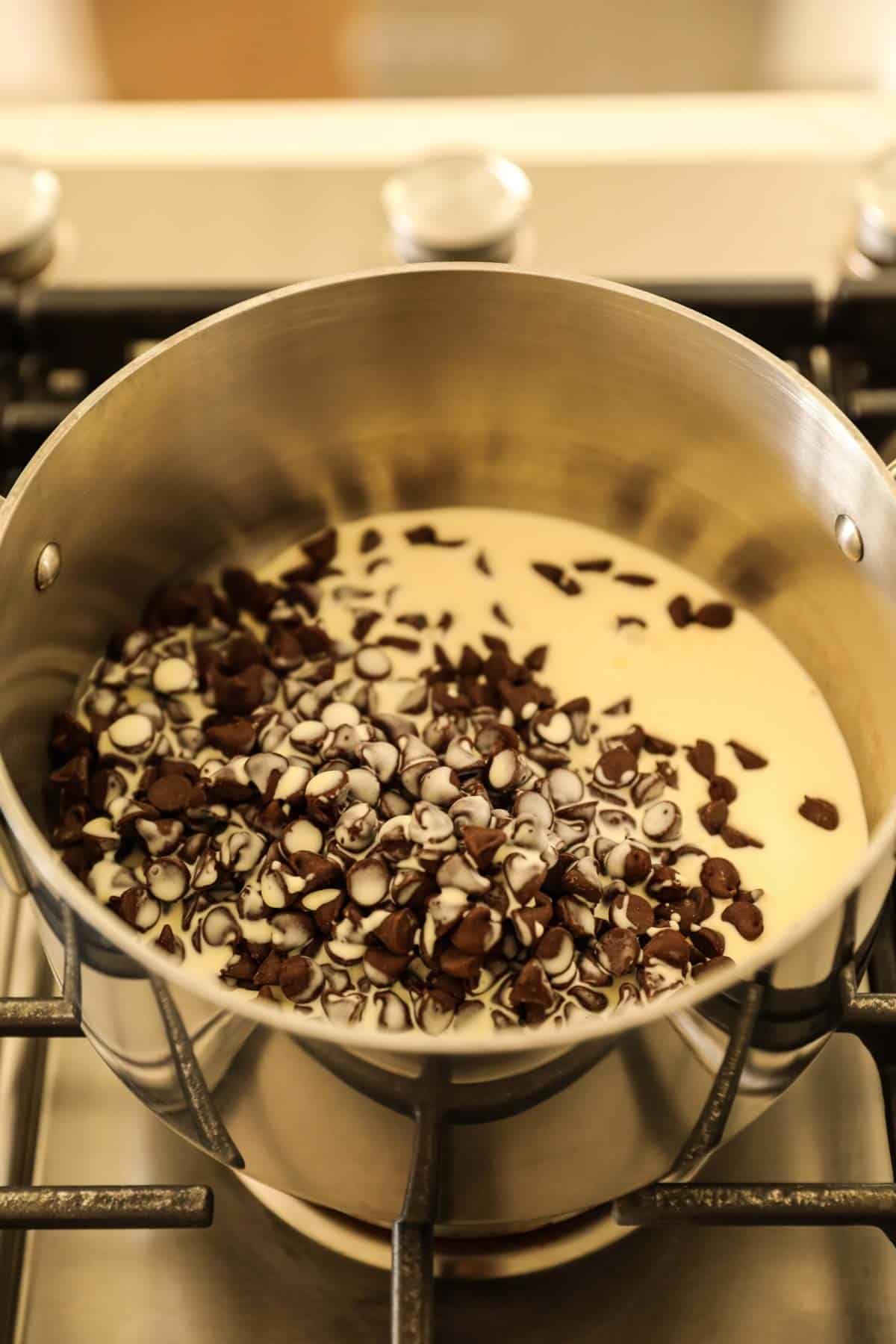 chocolate chips and heavy cream in a sauce pot on a cooktop