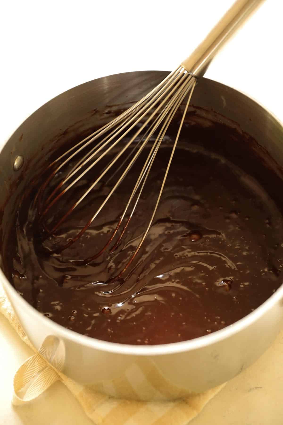 a pot of hot fudge with a whisk