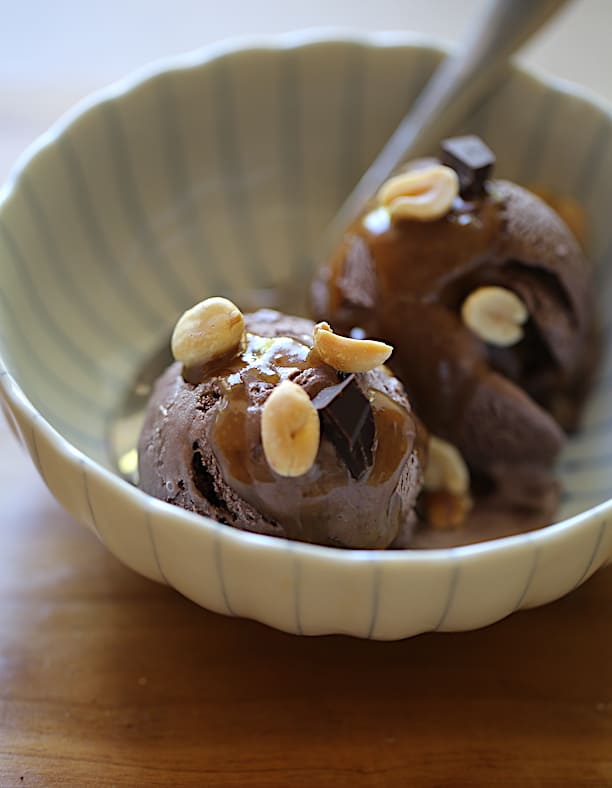 a blue strippped bowl with 2 scoops f chocolate ice cream drizzled with peanut butter sauce