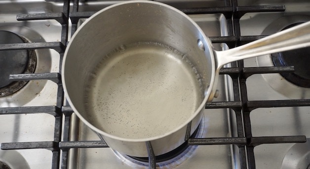a pot of clear sugar water simmering on a cooktop