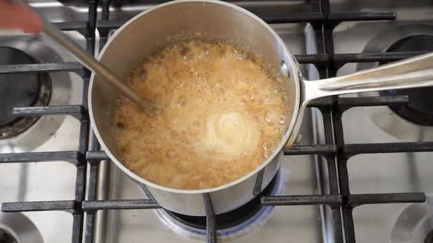 a poy of peanut better sauce simmering and boiling as it caramelizes