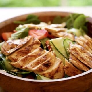 Grilled chicken on a bed of spinach salad with strawberries