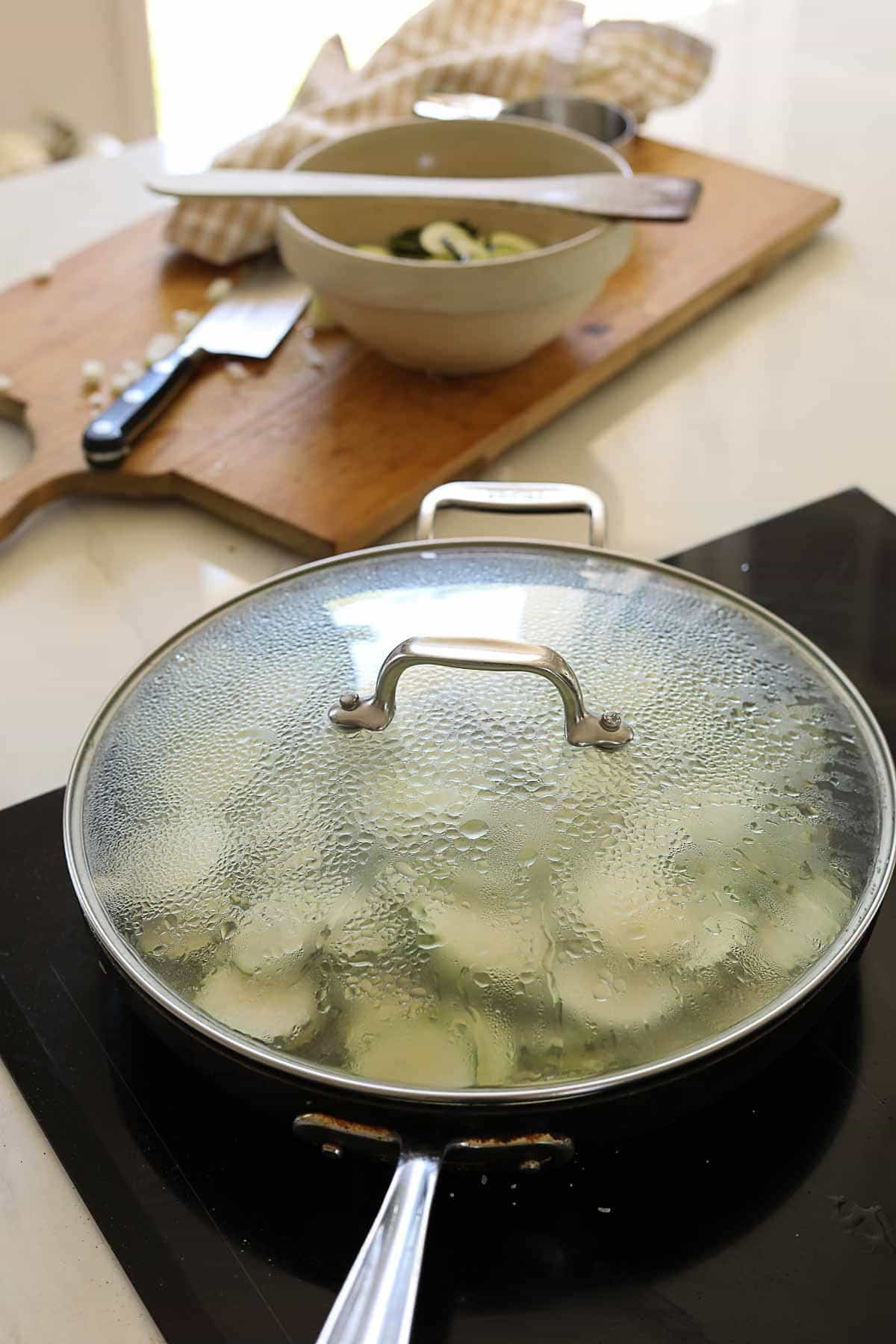steaming zucchini in a skillet.
