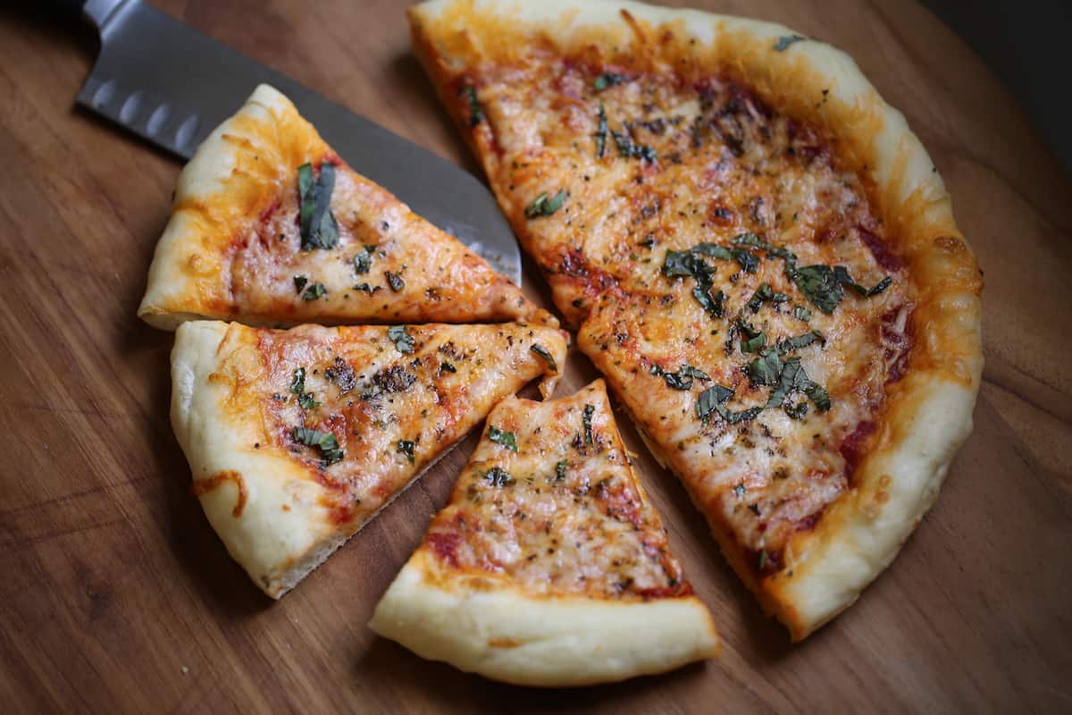 A slice of pizza sitting on top of a wooden cutting board, with Cheese