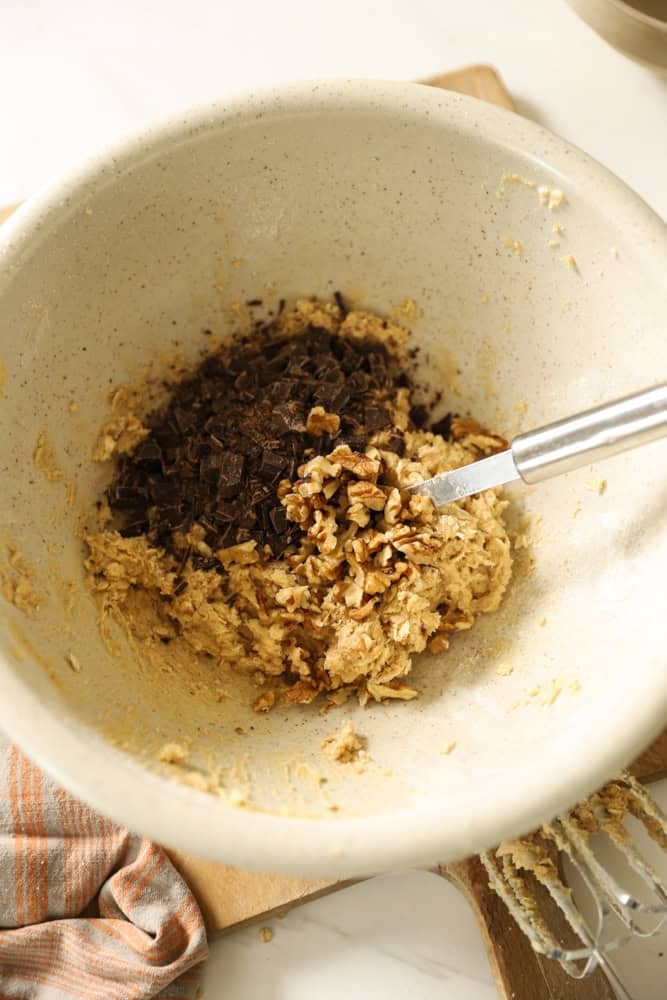 Cookie dough with dark chocolate, oatmeal being stirred in.