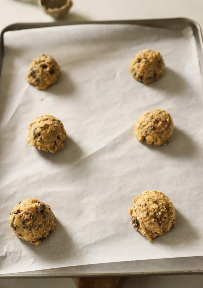 Cookie dough balls ready for the oven on a parchment lined cookie sheet.