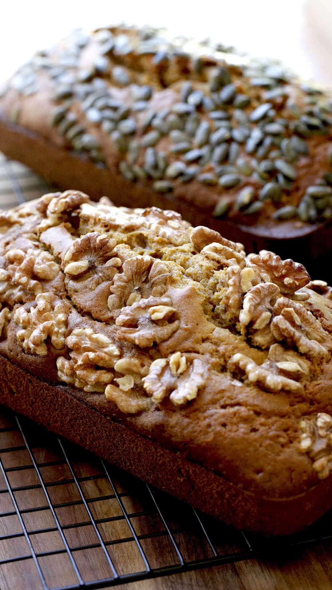 2 loaves of pumpkin bread cooling on a rack