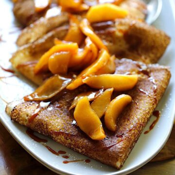 A platter of apple cinnamon crepes folded into triangles topped with caramel sauce