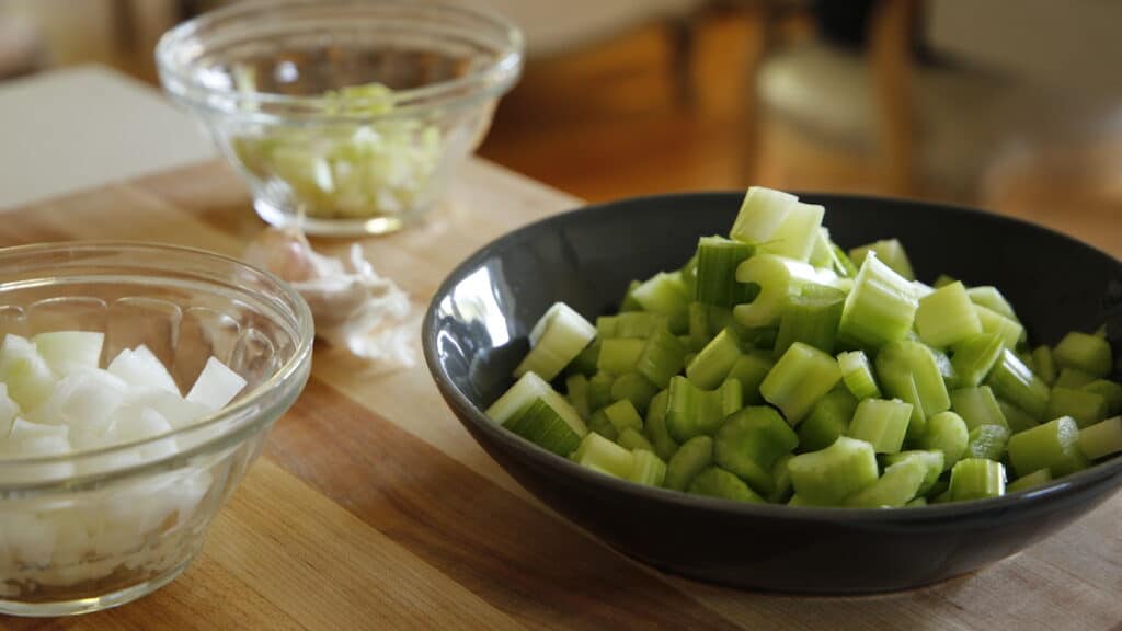 Prep bowls filled with chopped celery, onion, and leeks