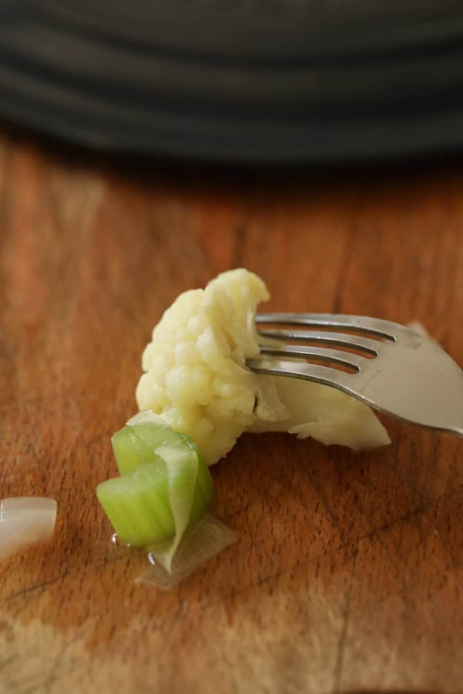 a fork piercing a piece of cauliflower and celery.
