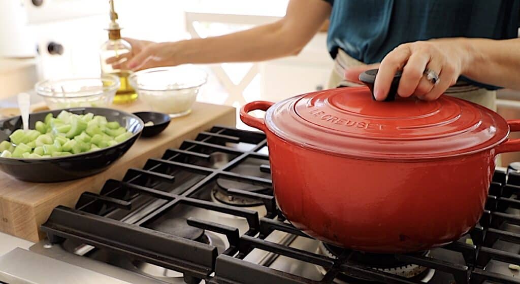 a red Dutch oven ready to cook vegetables for soup