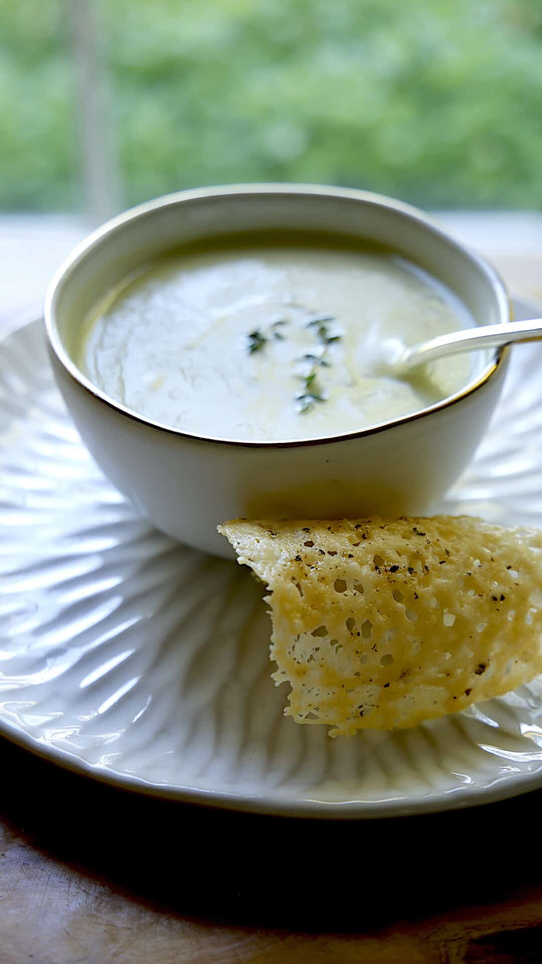 Vertical shot of Cream of Celery Soup with a parmesan tuile