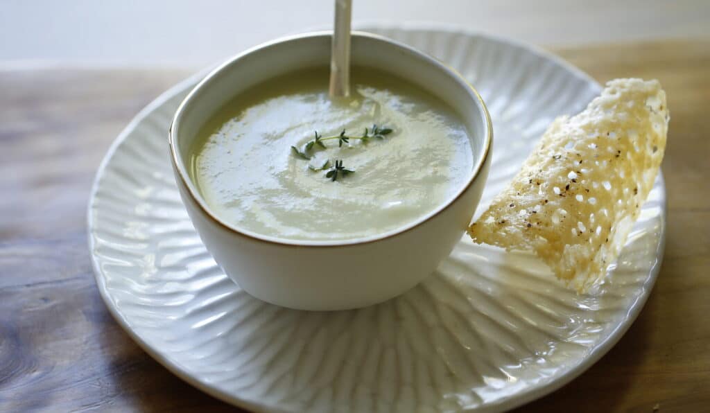 a bwl of cream of celery soup with parmesan tuile