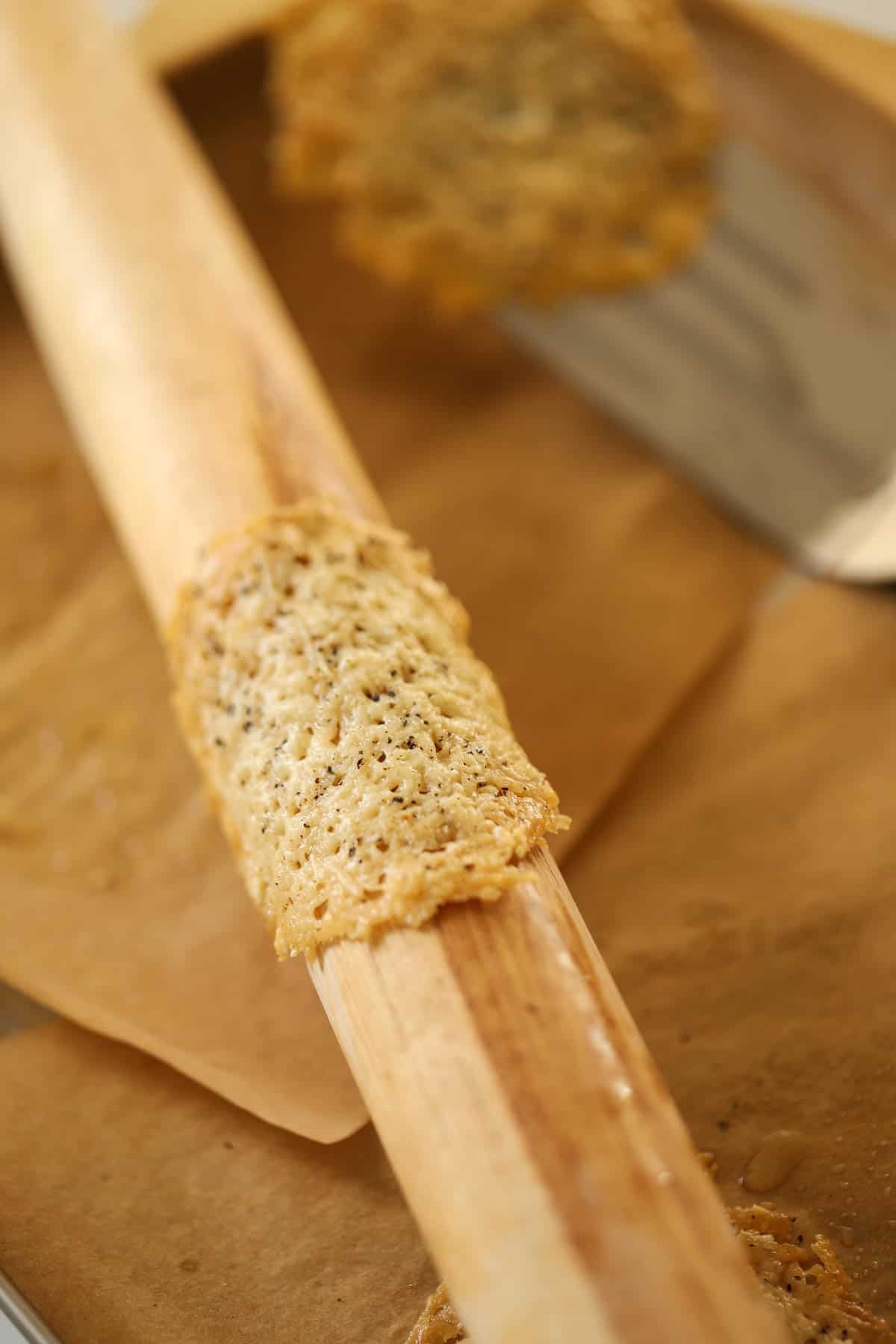 a parmesan tuile wrapped over a rolling pin to be formed.
