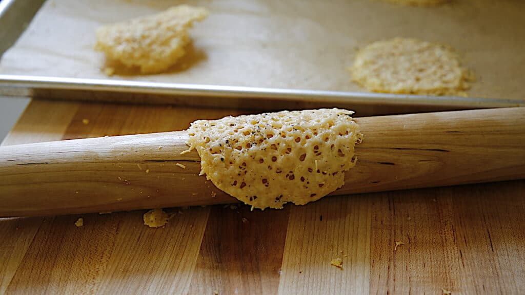 a baked parmesan tuile being formed around a french style rolling pin