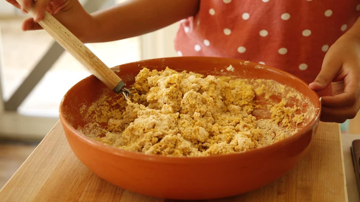 child stiring scone dough with a dough whisk