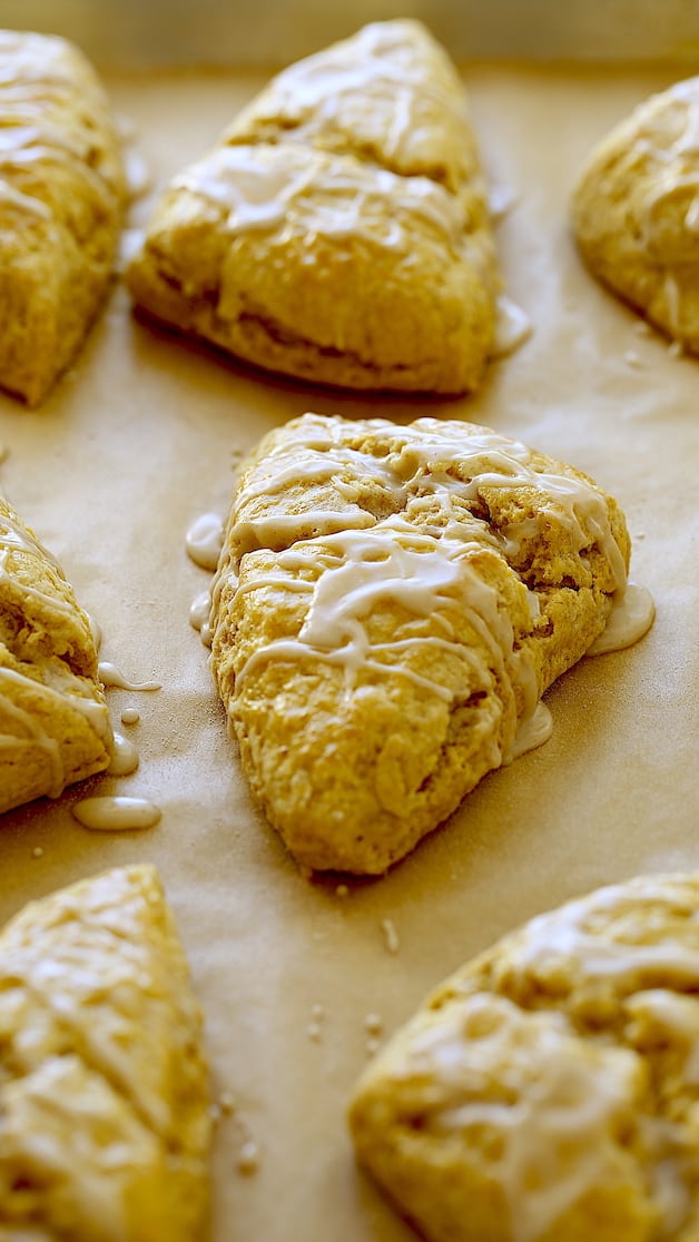 Vertical image of pumpkin scones on a baking sheet with chai glaze