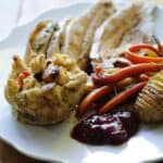 vertical image of a Thanksgiving plate with Turkey, sides, Stuffing and Cranberry Sauce