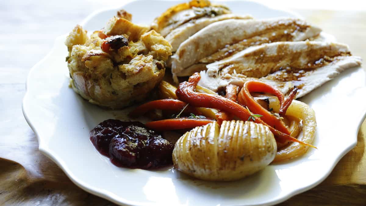 a white plate with turkey and graving and Thanksgiving sides on it