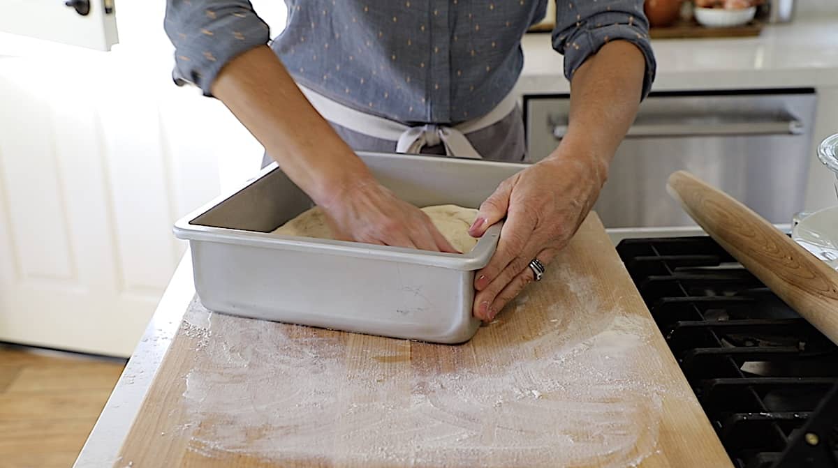 Pressing dough into a pan on a cutting board