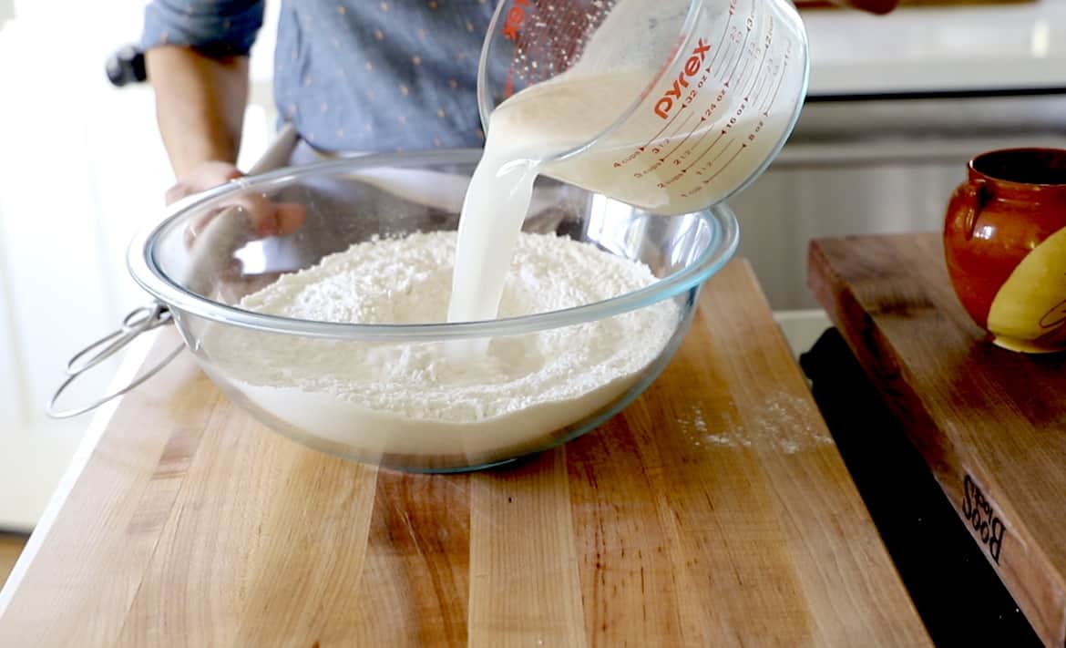 A person Adding yeast mixture to flour mixture