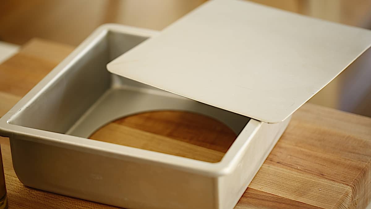 a square cheesecake pan with a removable bottom on a cutting board