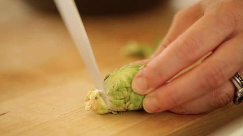 slicing ends of Brussels sprouts on a cutting board