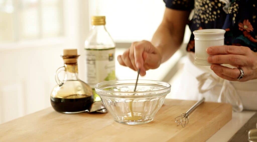 a person whisking together vinaigrette in a bowl