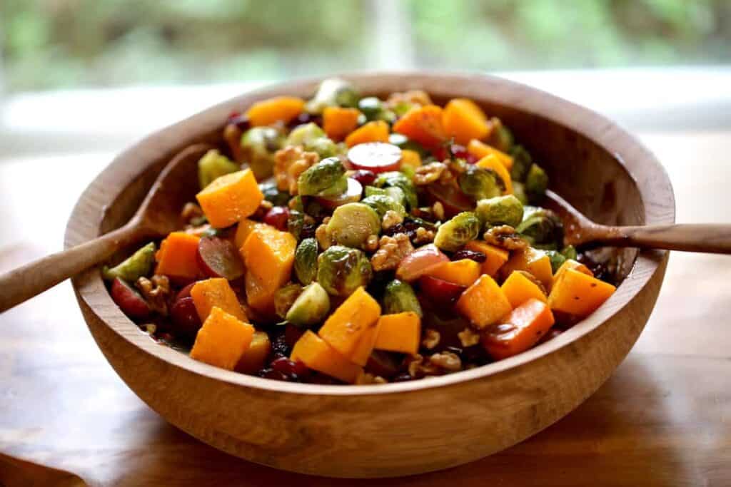 a harvest salad in a wooden bowl with wooden salad servers