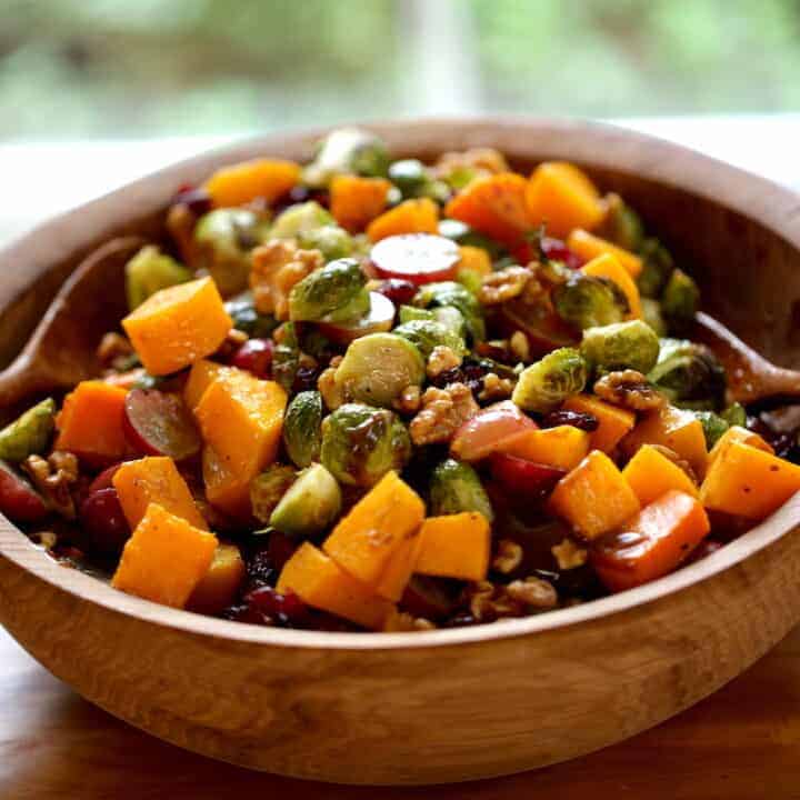 a harvest salad in a wooden bowl with wooden salad servers