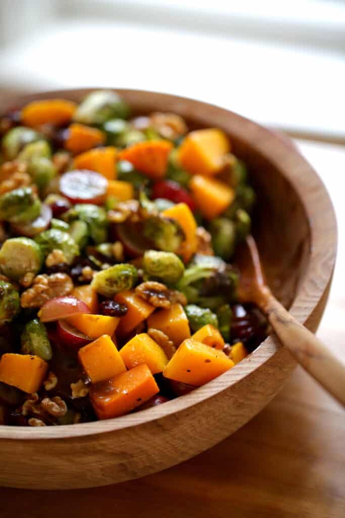 a vertical image of a wooden salad bowl filled with Harvest Salad