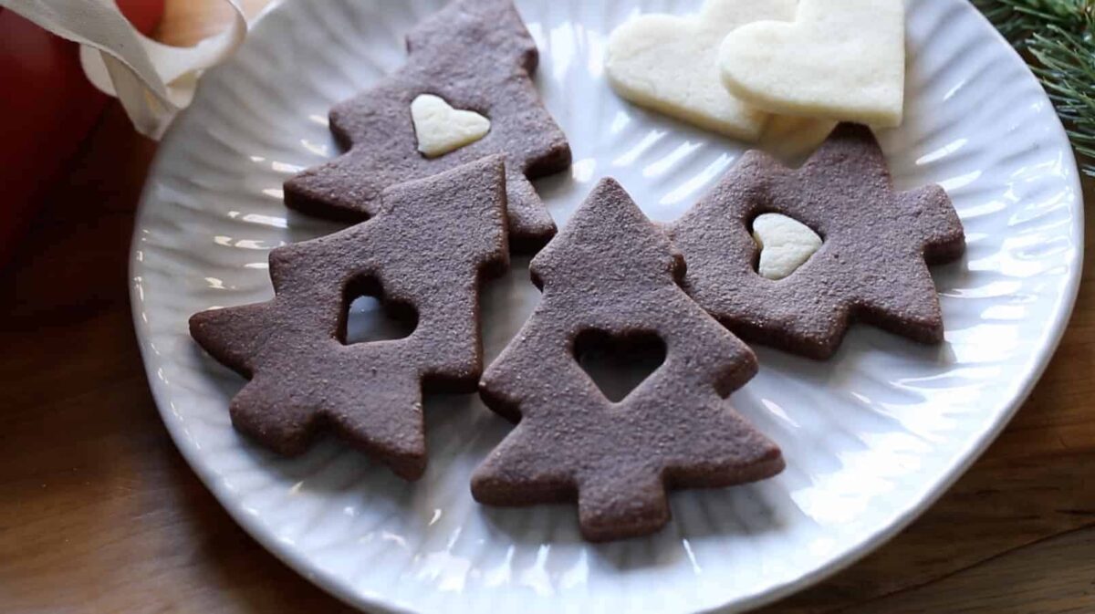 a plate of chocolate christmas tree cookies on a plate with sugar cookie hearts