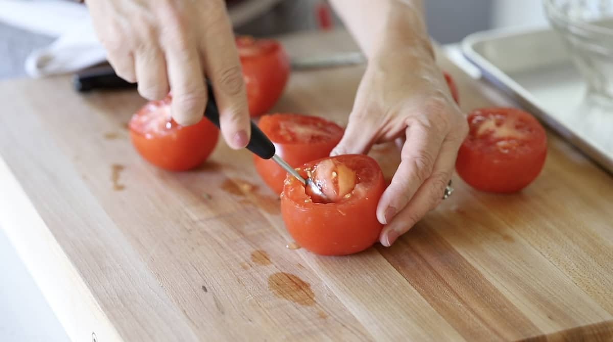 a person coring tomatoes with a melon baller