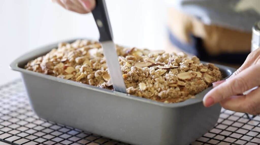 Loosening a crumb cake from its tin with a knife