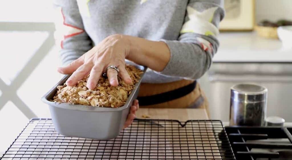 a person flipping a cake with crumb topping out of a loaf pan