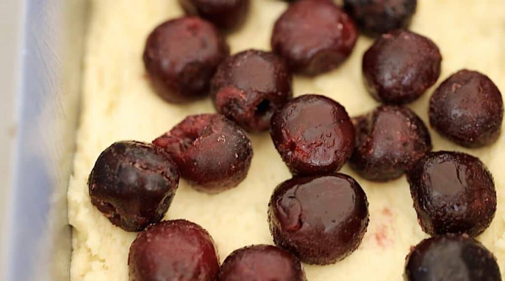 sour cherries in a loaf pan on top of cake batter