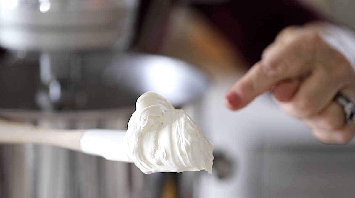 a person showing texture of whipped cream cheese and cream on a spatula